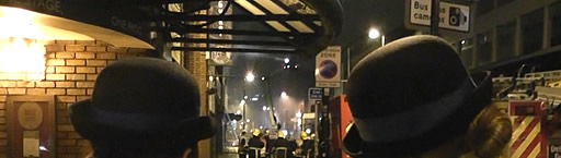 Two police officers look on as fire fighters tackle the blaze in Oldham Street