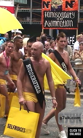 Gay men in speedos with shopping bags oblivious to fascists behind them